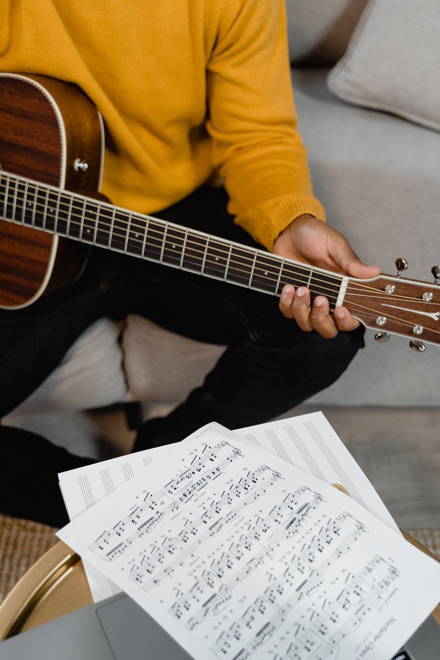 person playing a guitar beside a music sheet